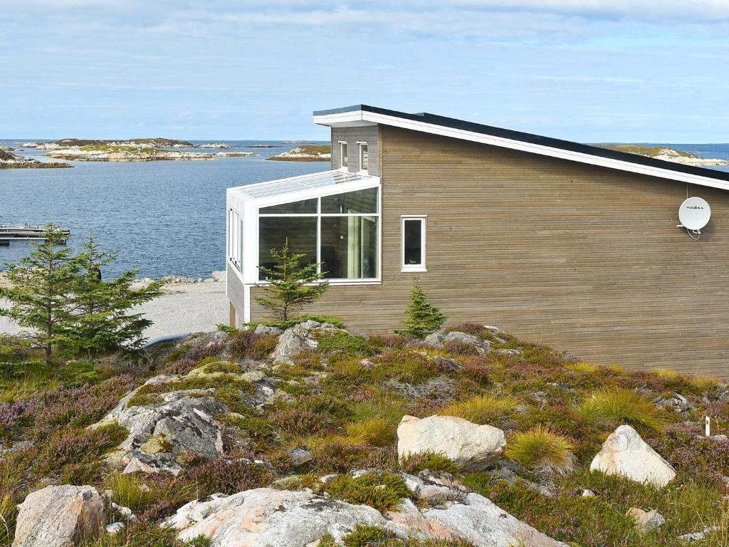 una casa en una colina junto a un cuerpo de agua en Holiday home Dyrvik III, en Dyrvik
