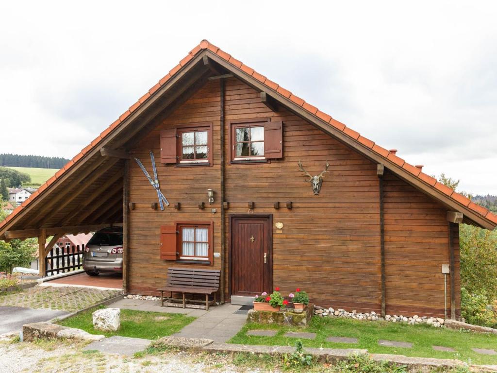 una pequeña casa de madera con un banco delante en Chalet in Hinterrod Thuringia with sauna en Eisfeld