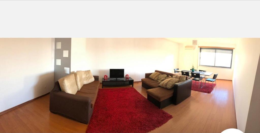 una sala de estar con 2 sofás y una alfombra roja en Wonderful apartament Lisbon, en Montijo