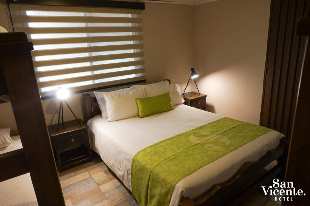 a bedroom with a bed with a green blanket on it at Hotel Termales San Vicente in Santa Rosa de Cabal