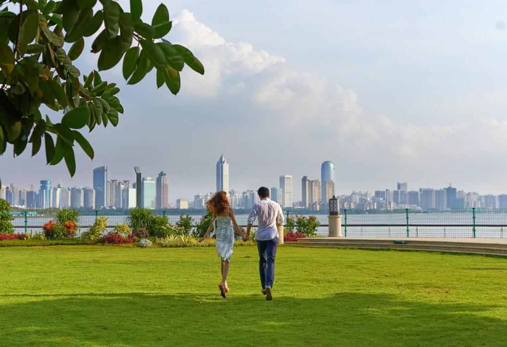 a man and woman walking in a park with a city in the background at InterContinental Haikou Seaview, an IHG Hotel in Haikou