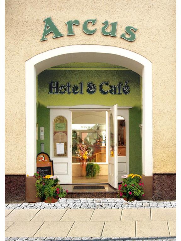 an entrance to a hotel and cafe with flowers in the doorway at Hotel Arcus in Elsterwerda