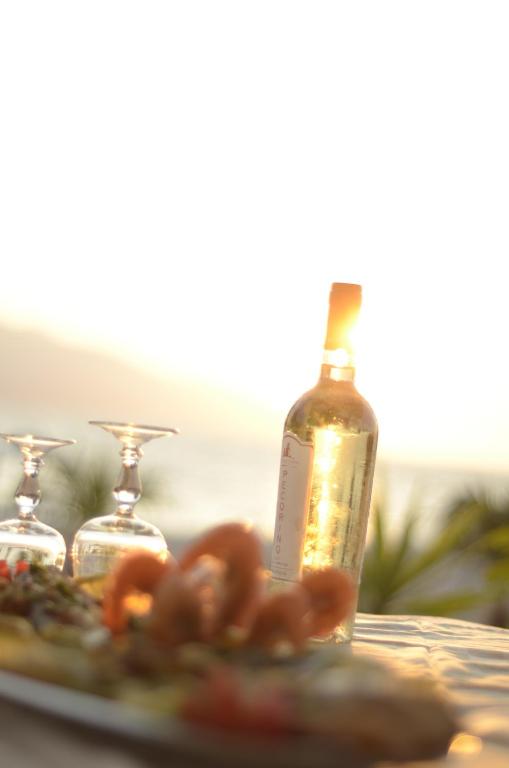 a bottle of wine sitting next to a plate of food at Hotel Garden in Vlorë