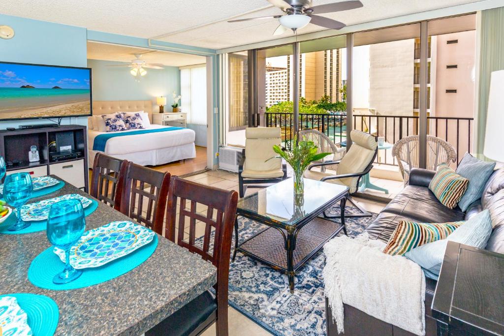 een woonkamer met een bank en een tafel met stoelen bij Beach Lover's Haven, Cozy Condo with Ocean Views and Free Parking in Honolulu