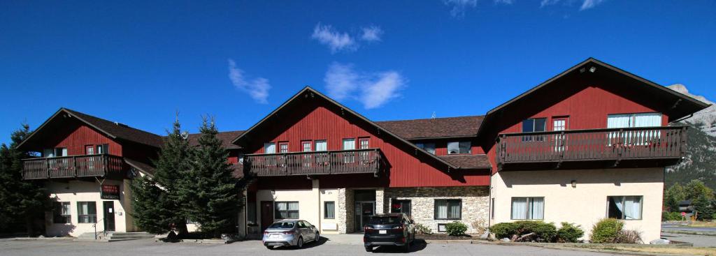 a large red and white building with cars parked in front at Bighorn Inn & Suites in Canmore