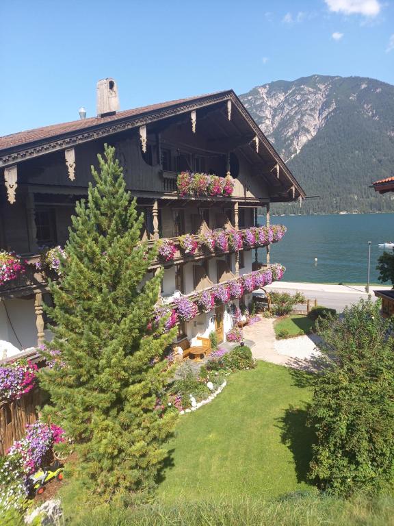 un edificio con fiori e un albero di fronte di Seepension Knappenhof a Pertisau