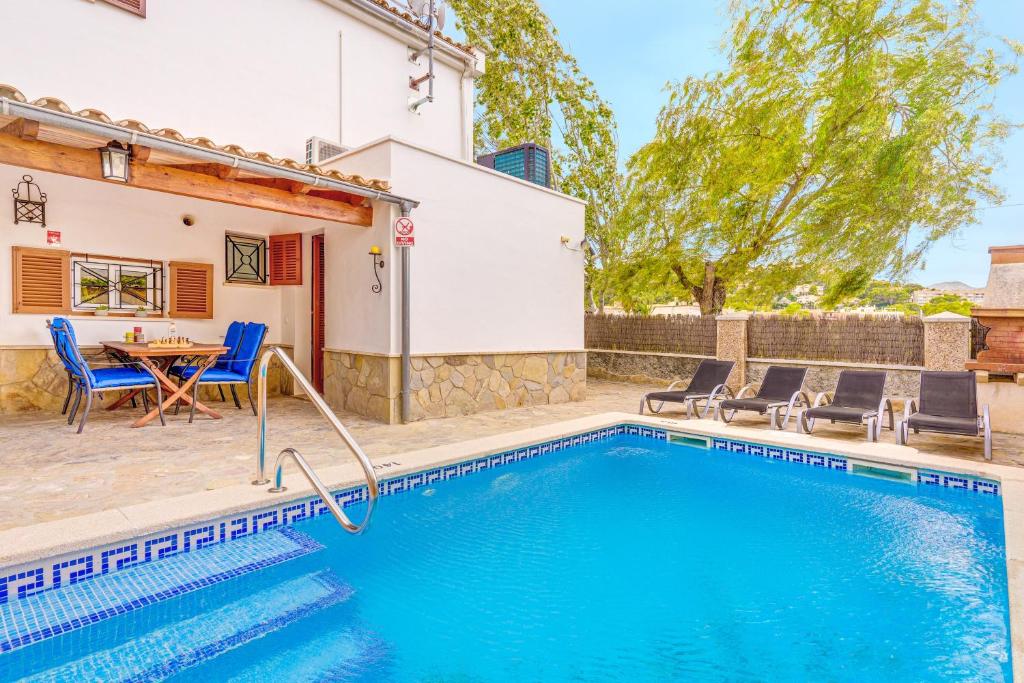 a swimming pool with a table and chairs next to a house at Villa Pintor in Port de Pollensa