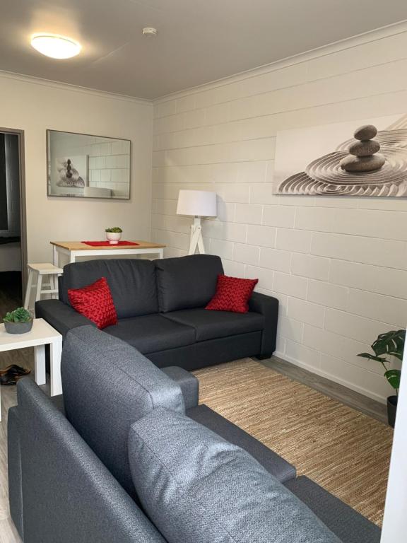 a living room with a blue couch and red pillows at Walk to Lamberts Beach with Wi-fi and Netflix in Slade Point