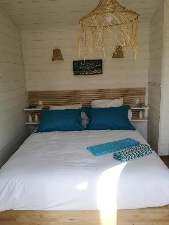 a bedroom with a white bed with blue pillows at la cabane vensac ocean montalivet in Vensac