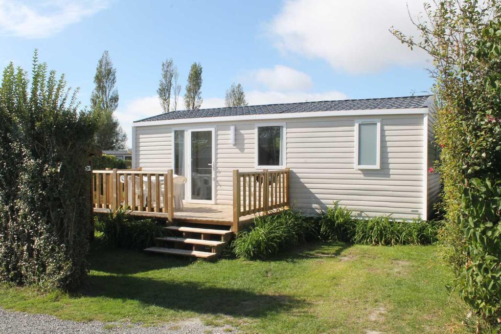 een wit huis met een veranda en een terras bij Camping Le Tarteron in Le Crotoy