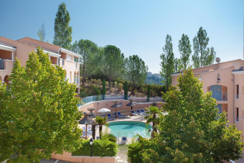 グレウー・レ・バンにあるRésidence Odalys La Licorne de Haute Provenceのスイミングプールと木々のあるリゾートの景色を望めます。