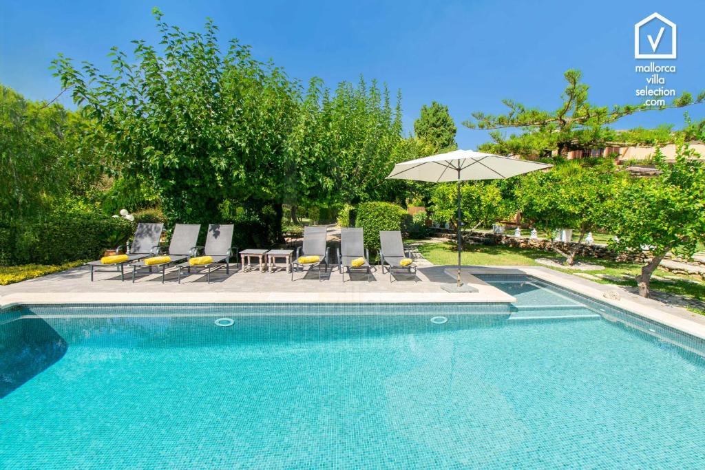 a swimming pool with chairs and an umbrella at Finca MARIPOSA Alcudia in Alcudia