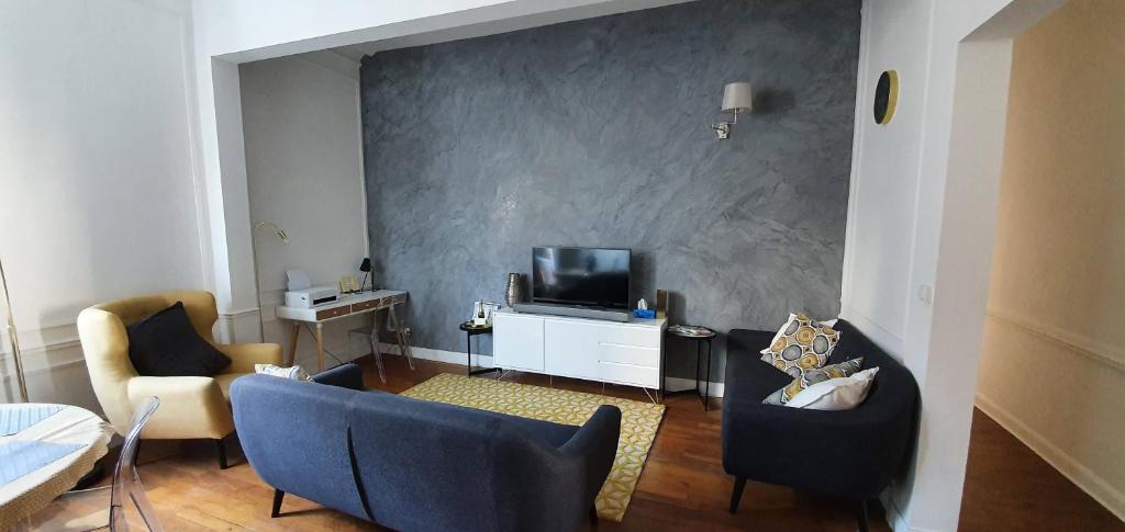 un salon avec un canapé et une télévision dans l'établissement L'Ecu : un Haussmannien accueillant!, à Reims