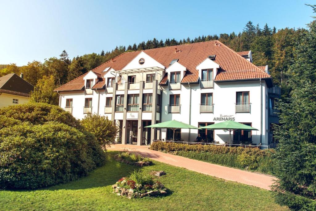 ein großes weißes Gebäude mit grünen Sonnenschirmen davor in der Unterkunft Aktivhotel Inselsberg in Tabarz