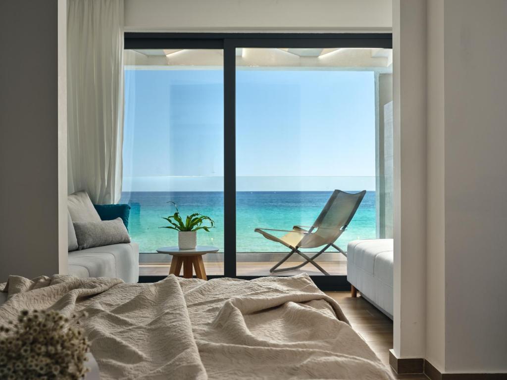 a bedroom with a bed and a view of the ocean at Cavo Orient Beach Hotel & Suites in Tragaki