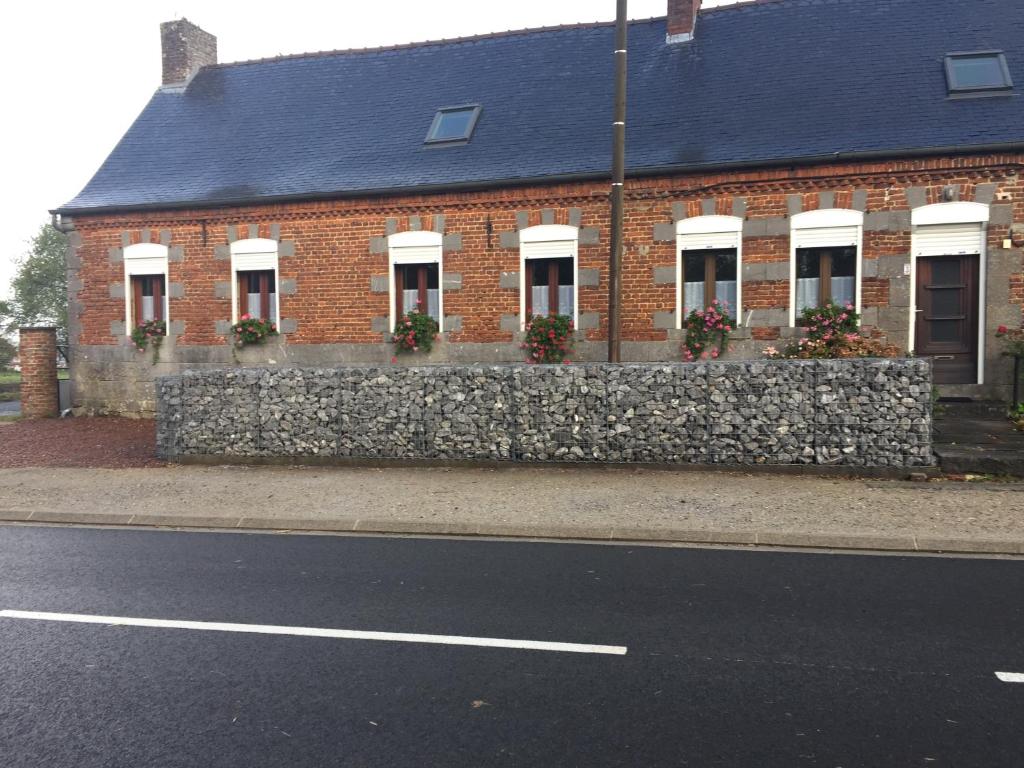 a brick building with a stone wall next to a street at Le Clergite in Clairfayts
