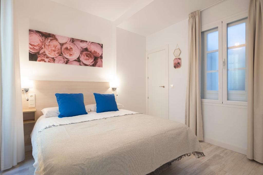 una camera bianca con letto e cuscini blu di MOLINO CORTEZA DELUXE 6 pax a Granada