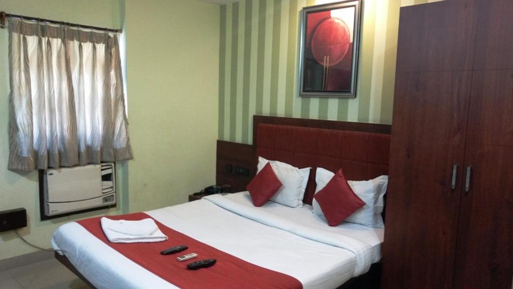1 dormitorio con 1 cama grande con almohadas rojas y blancas en Bhammar's Inn - A Pure Veg, en Calcuta