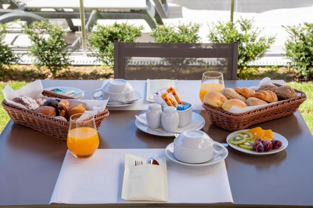 uma mesa azul com cestas de alimentos para pequeno-almoo e sumo de laranja em Luna Hotel de Tbua na Tbua