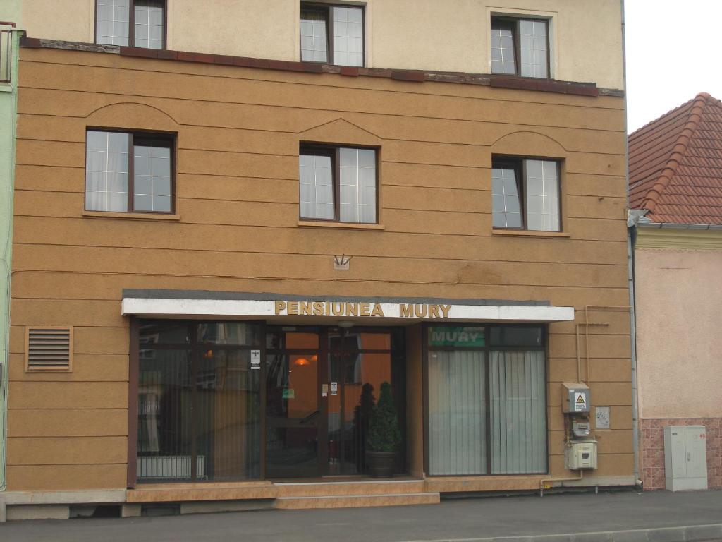 een bruin gebouw met een bord voor een winkel bij PENSIUNEA MURY in Braşov