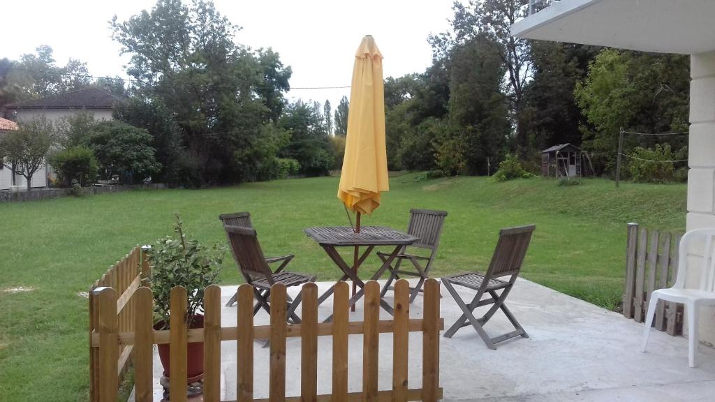 a patio with a table with an umbrella and chairs at chez sylvette in Quinsac