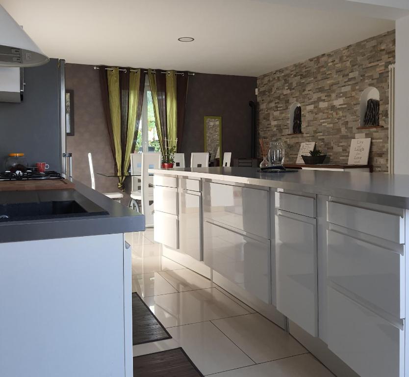 a kitchen with white cabinets and a stone wall at Gite Ardennes in Deville