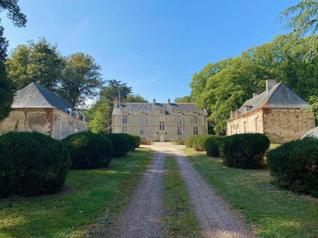 eine Straße, die zu einem großen Schloss mit Büschen führt in der Unterkunft Château de Moulins in Moulins-le-Carbonnel