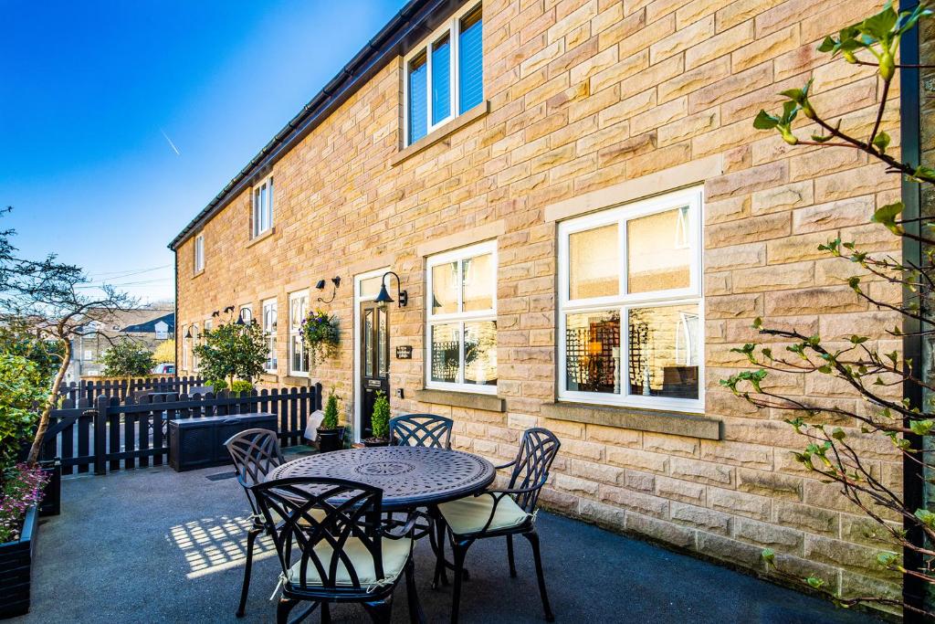 a patio with a table and chairs in front of a brick building at Buxton centre cosy cottage with free secure parking in Buxton