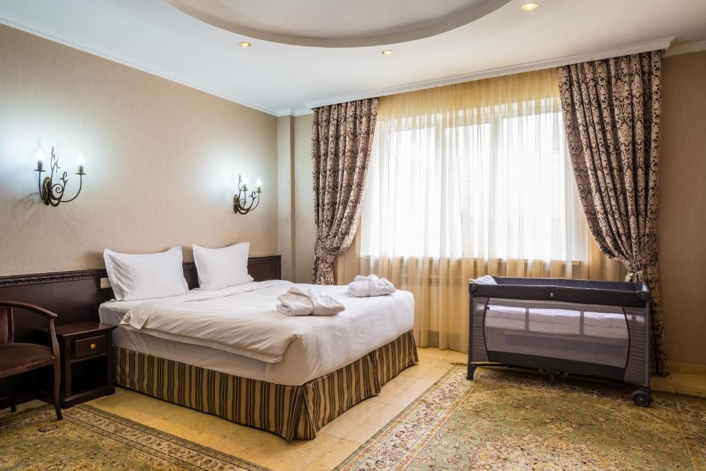 a bedroom with a bed and a desk and a window at Royal Petrol Hotel in Almaty