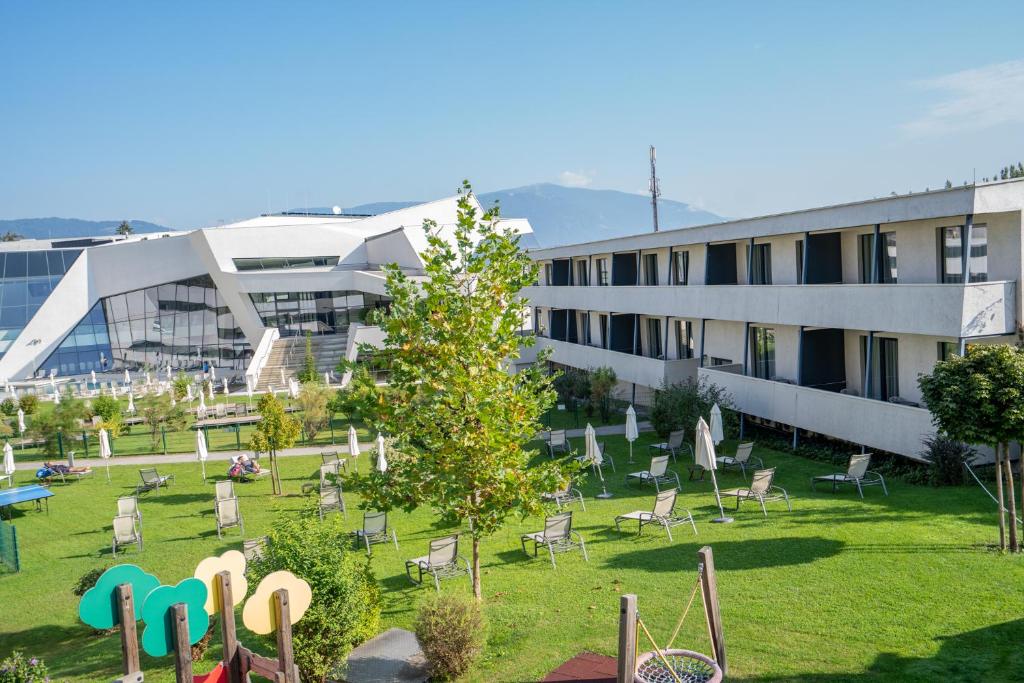 um edifício com um quintal com cadeiras e uma árvore em Appartementhaus Karawankenhof em Villach