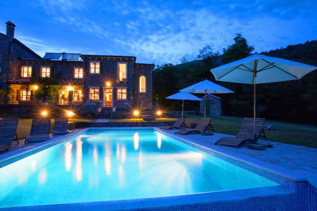 una piscina con sillas y sombrillas frente a una casa en Villa Bazjaki - Beautiful stone villa in Istria with private pool en Livade