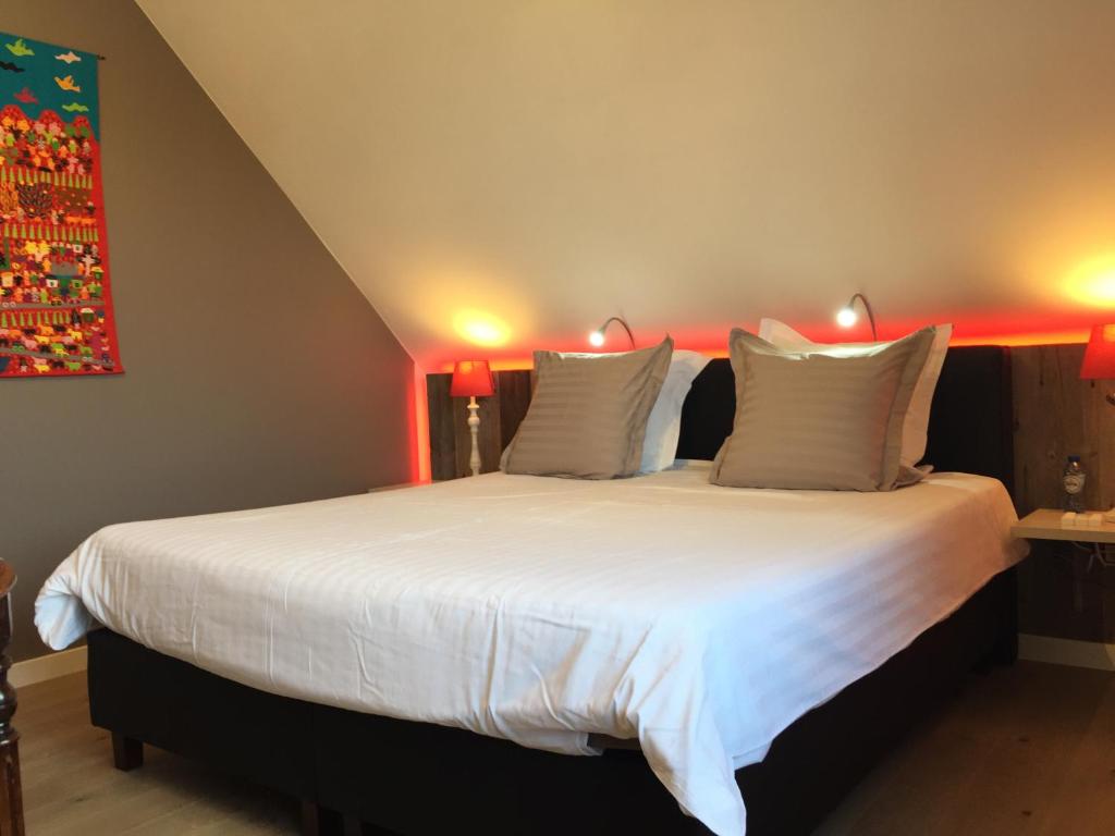 a bedroom with a large white bed with red lighting at B&B Bella en Basiel in Bruges