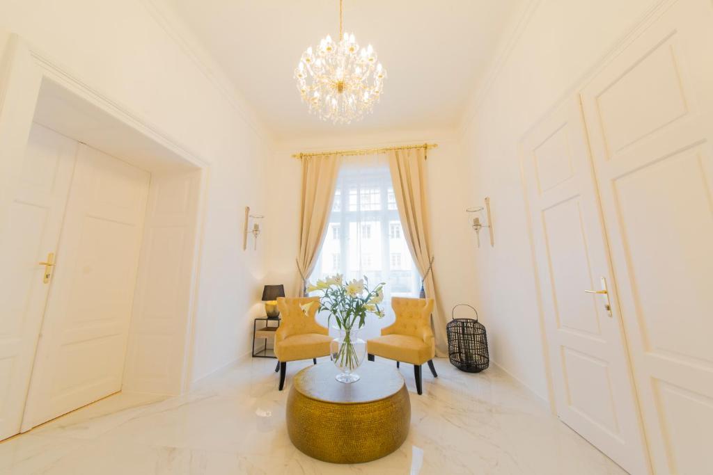 a living room with a table and chairs and a chandelier at Palais Gutenberg le Petit in Klagenfurt