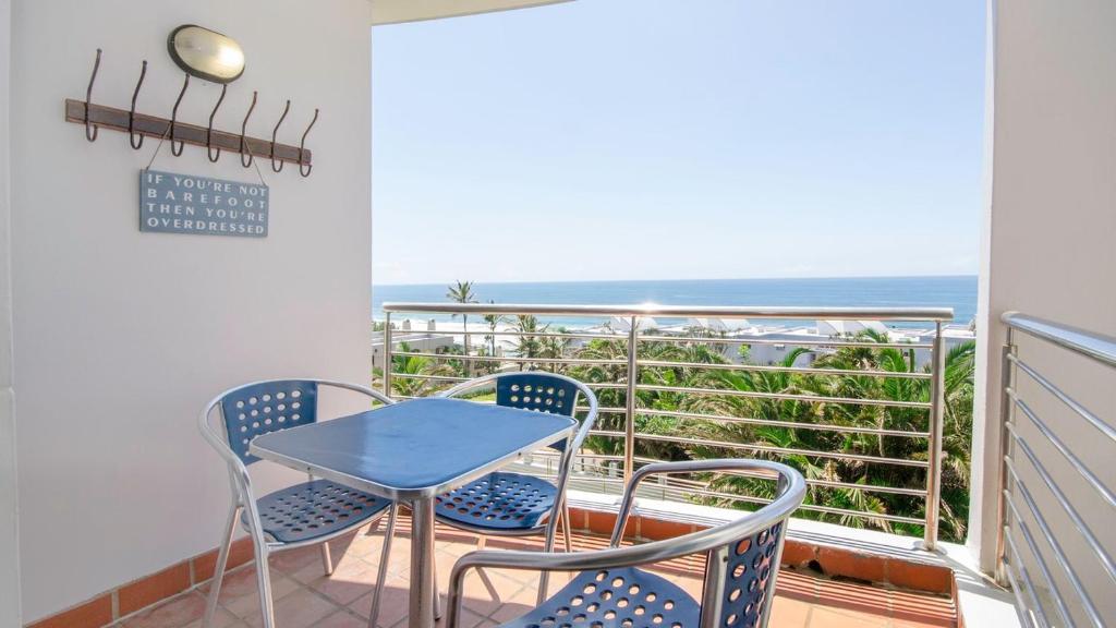 a balcony with a table and chairs and the ocean at Ocean Breeze at 92 Chaka Cove in Ballito