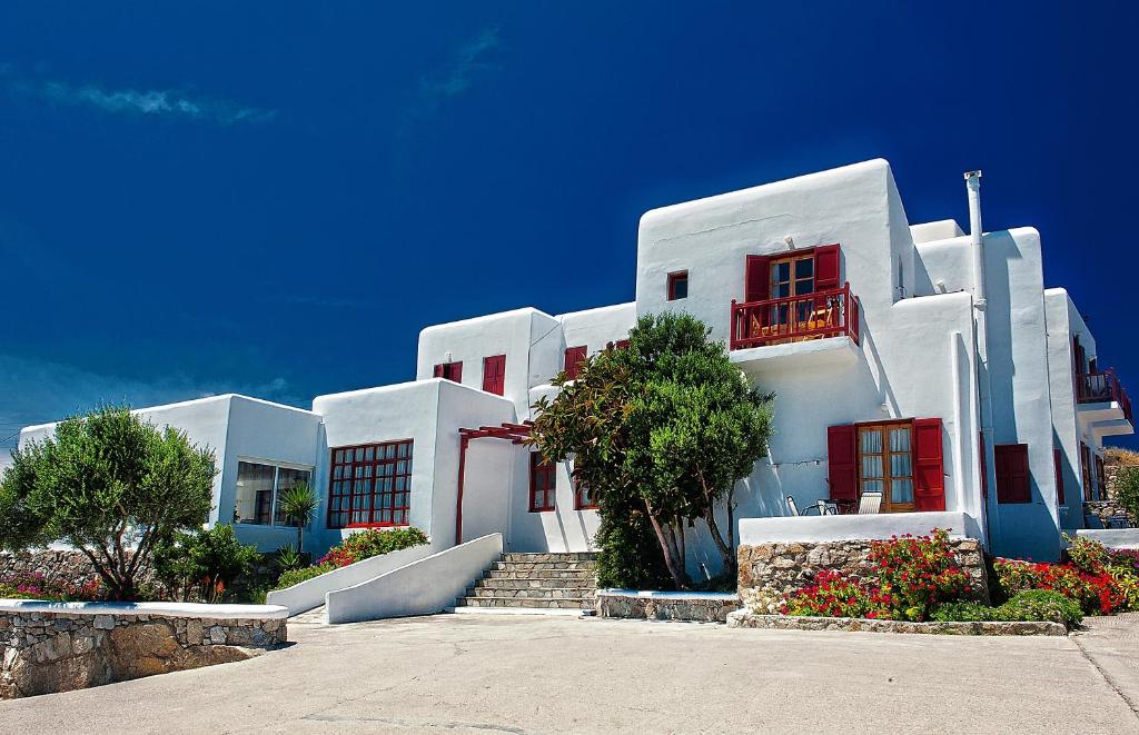 a large white building with red windows and stairs at Hotel Charissi in Mikonos