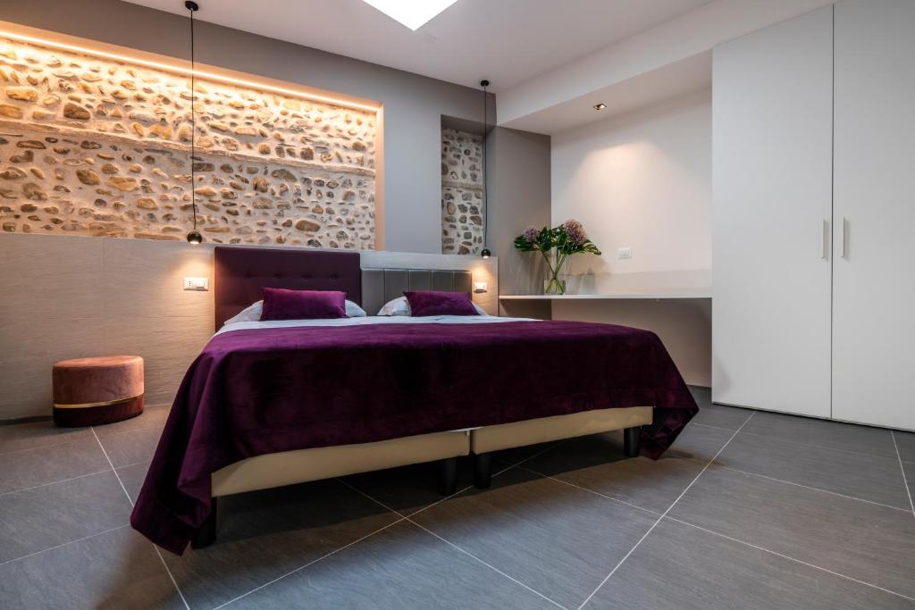 - une chambre avec un grand lit et des oreillers violets dans l'établissement Astoria Boutique Apartments, à Bologne