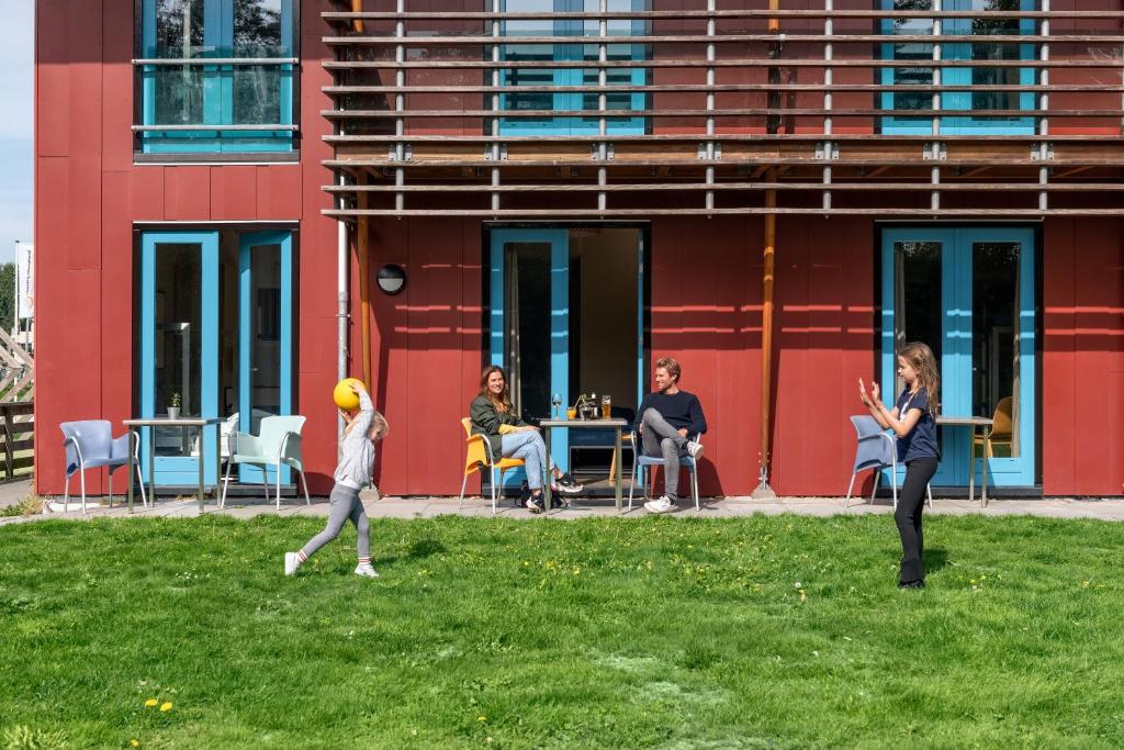 um grupo de pessoas andando na grama em frente a um edifício em Stayokay Hostel Texel em Den Burg