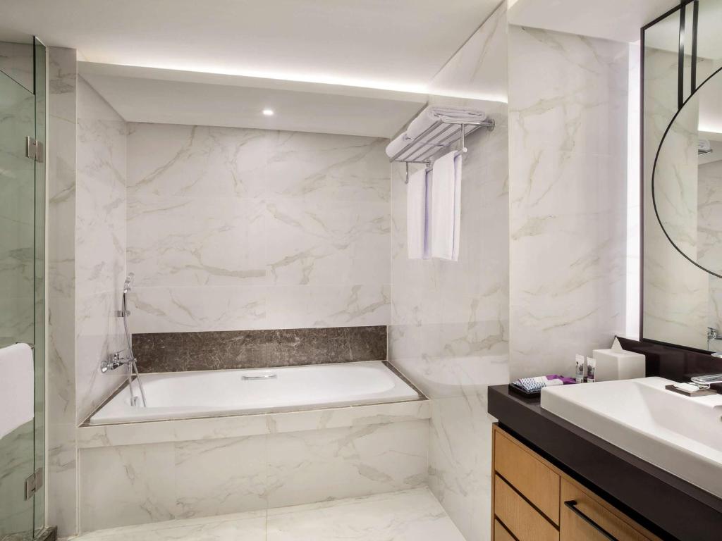 a bathroom with a tub and a sink at Mercure Jakarta Batavia in Jakarta