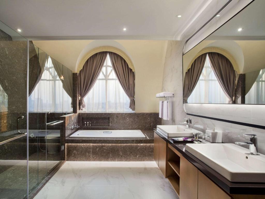 a bathroom with a tub and two sinks and a shower at Mercure Jakarta Batavia in Jakarta