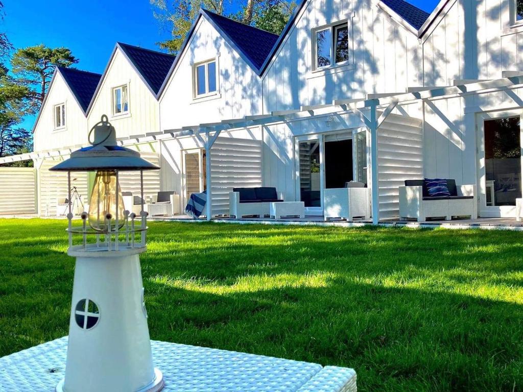 a white house with a lighthouse in the yard at Domki Gustav in Międzywodzie