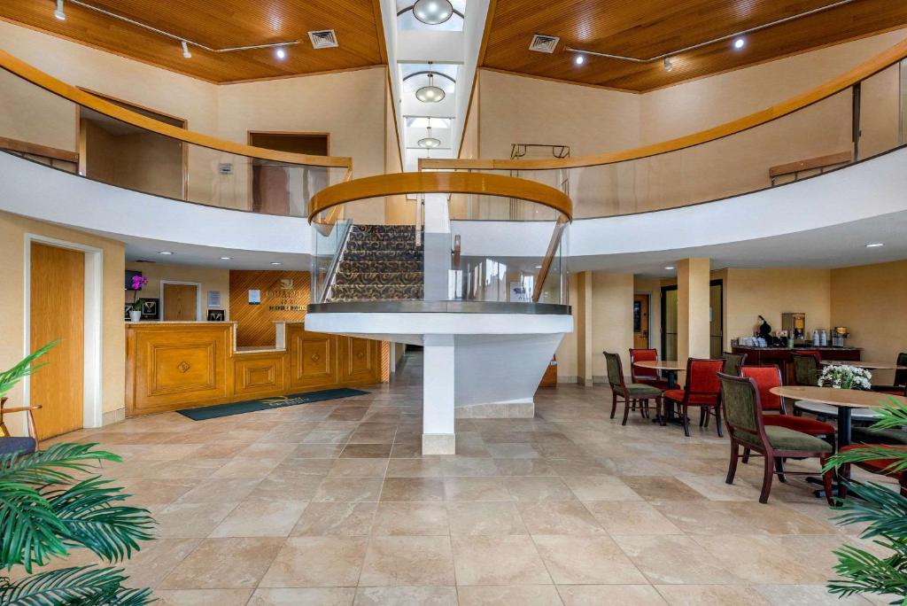 a lobby with a restaurant with a staircase and tables at Quality Inn Fort Wayne in Fort Wayne