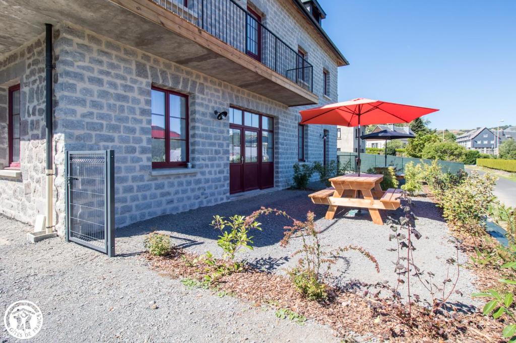 a picnic table with an umbrella next to a building at Gîte de Granit ROSE in Besse-et-Saint-Anastaise