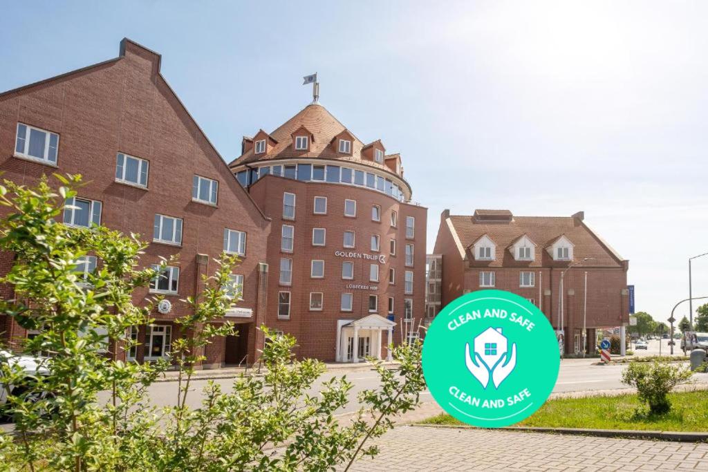 un edificio con una señal verde delante de él en Golden Tulip Luebecker Hof en Lübeck