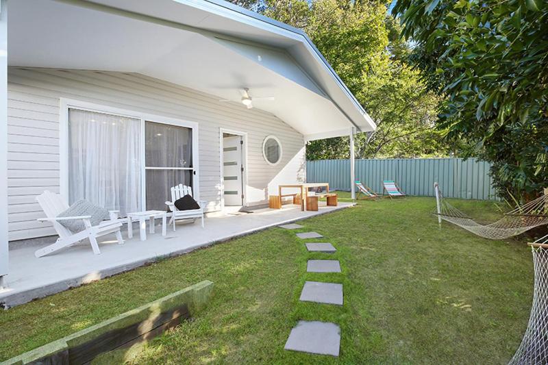 a white house with a patio and a yard at Salty Kisses Holiday House in Point Clare