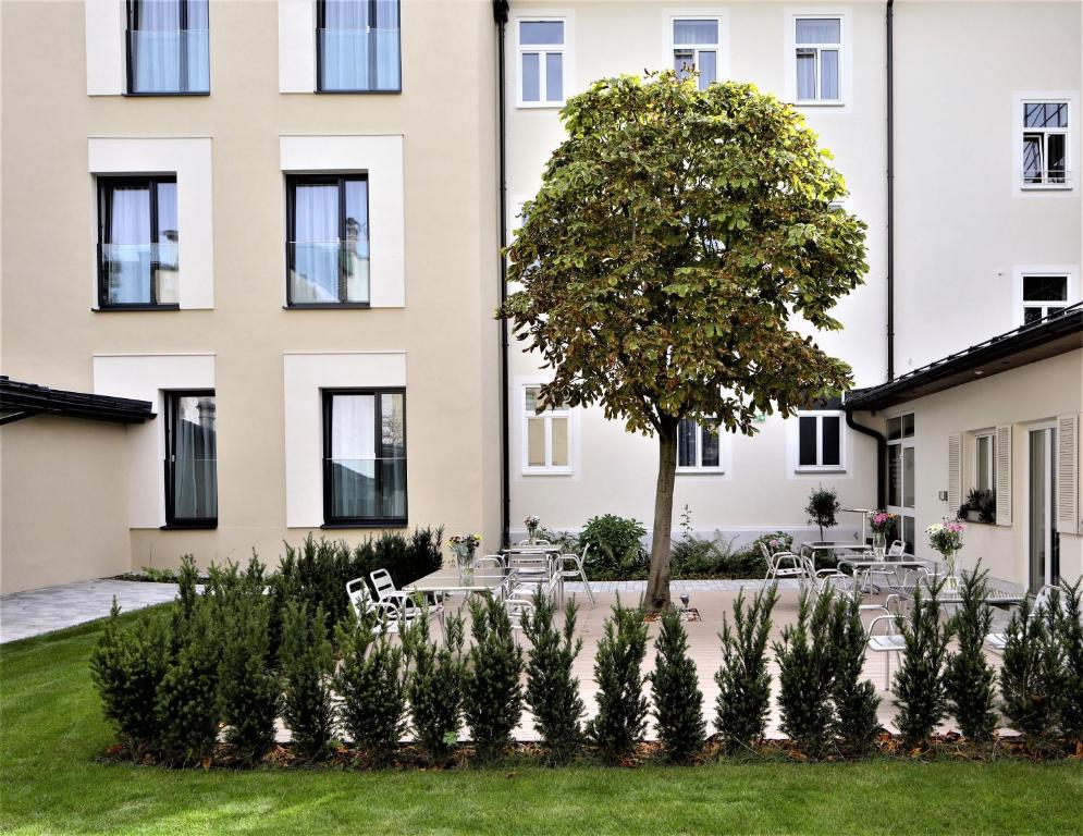 un edificio con un árbol delante de un patio en Das Jedermann Boutiquehotel mit Stadtgarten en Salzburgo