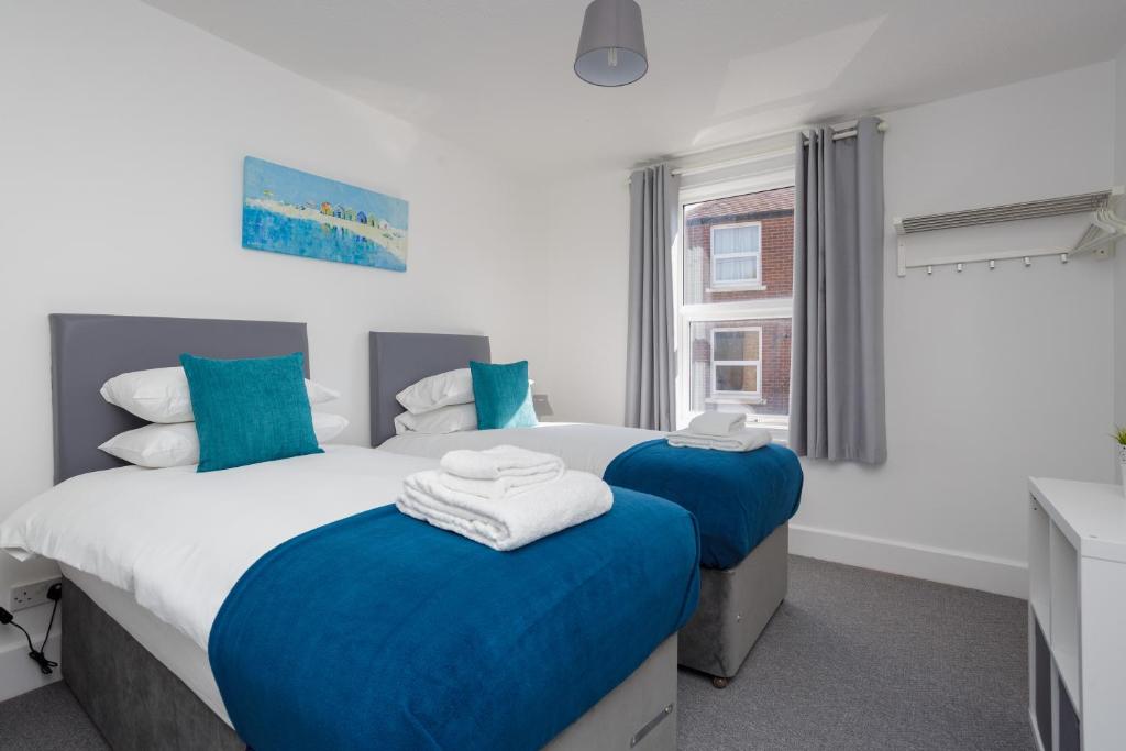 2 łóżka w sypialni w kolorze niebieskim i białym w obiekcie Stopover at LOWCAY APARTMENT C great for workers and groups w mieście Portsmouth