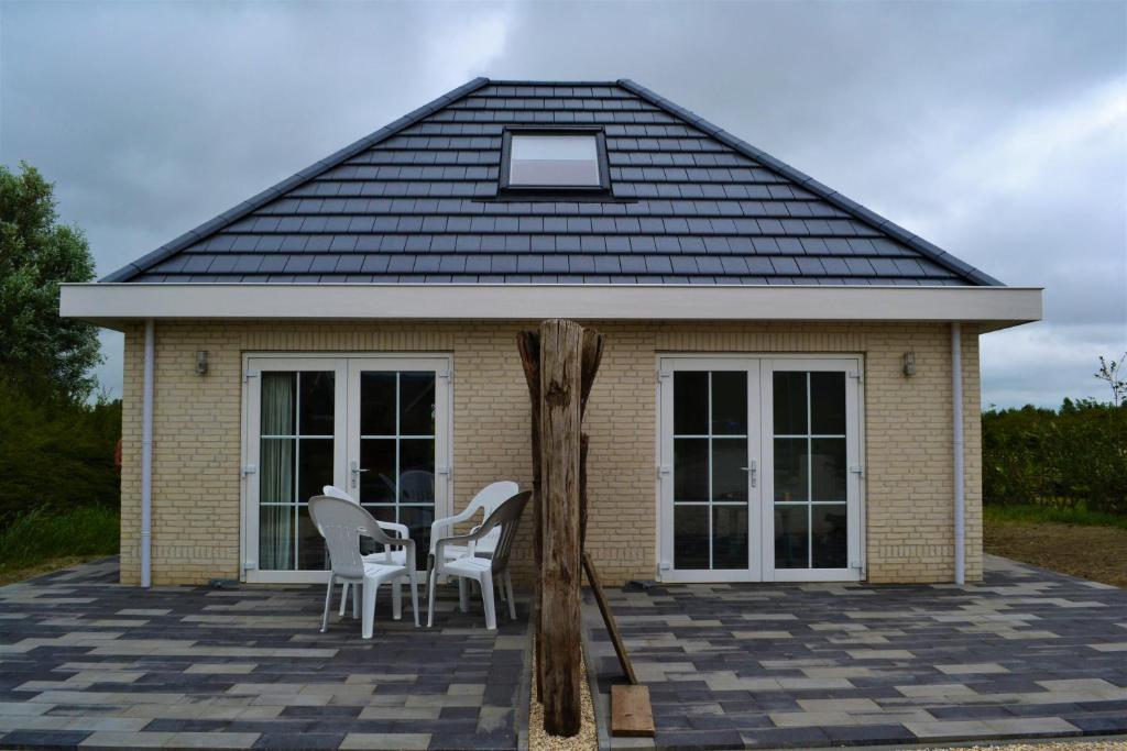 een huis met stoelen en een tafel ervoor bij Vakantiewoning aan duinen en zee in Dishoek in Dishoek