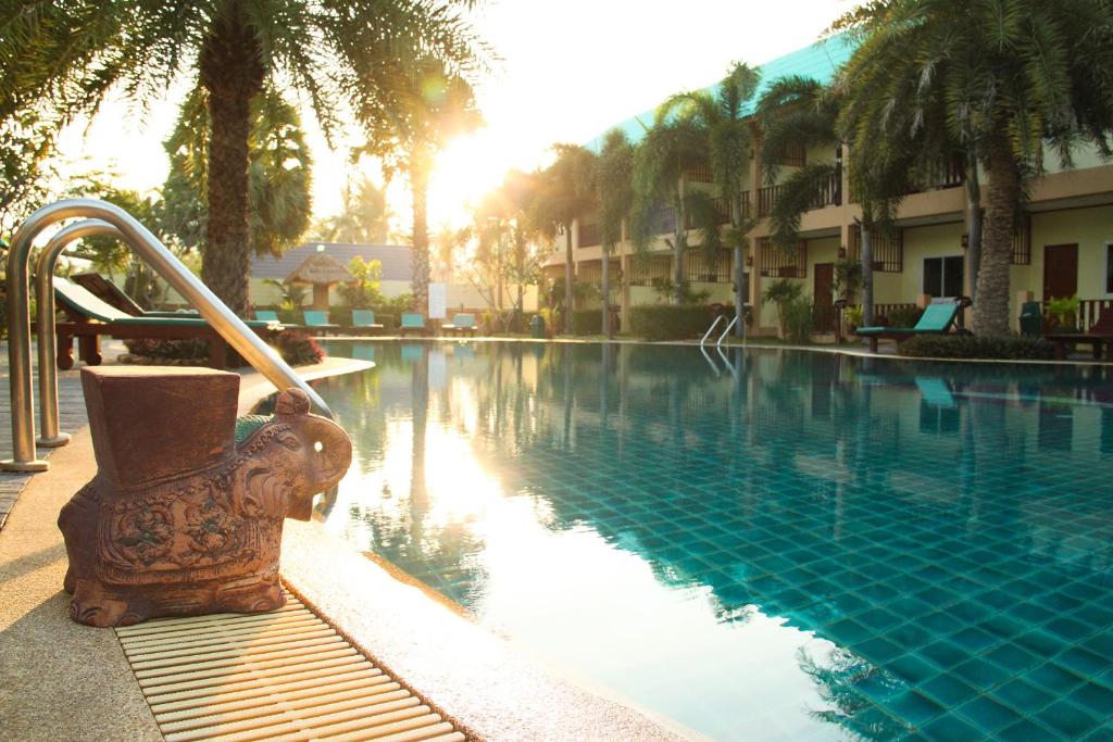 a swimming pool with a fountain next to a resort at The Green Beach Resort in Sam Roi Yot