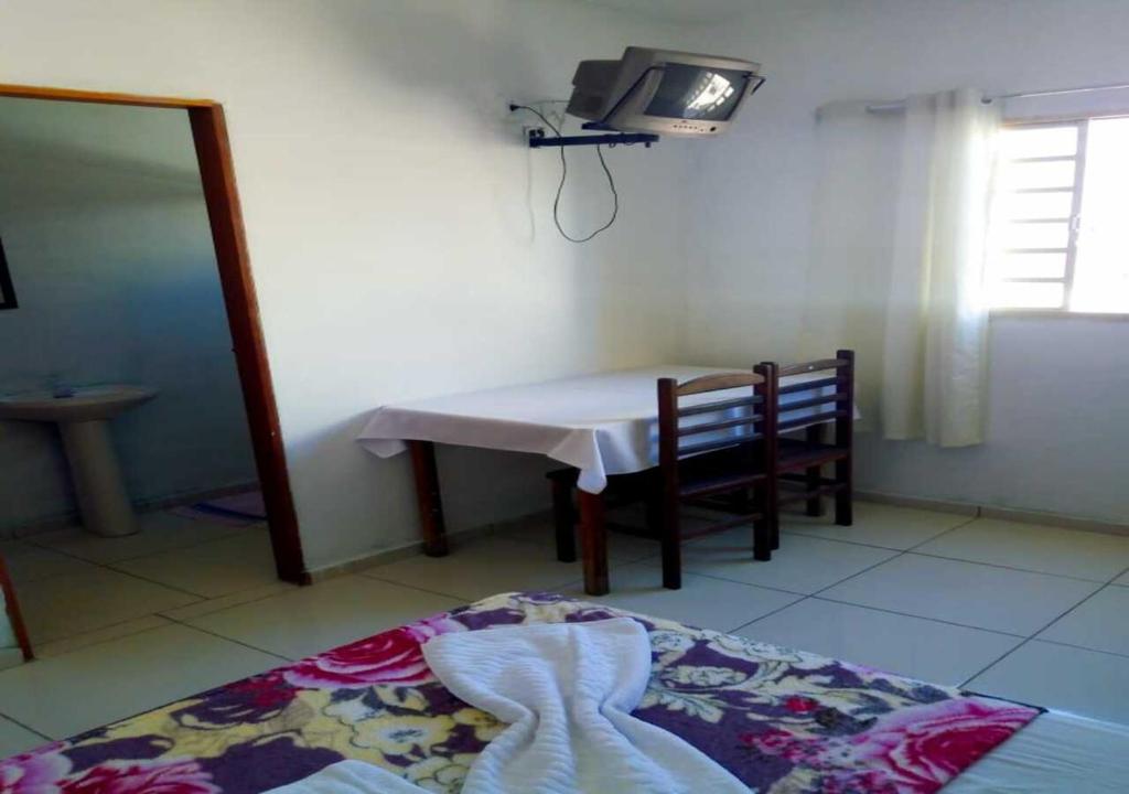 a room with a bed and a table and a tv at Pousada Brasil - Self Check-in in Aparecida