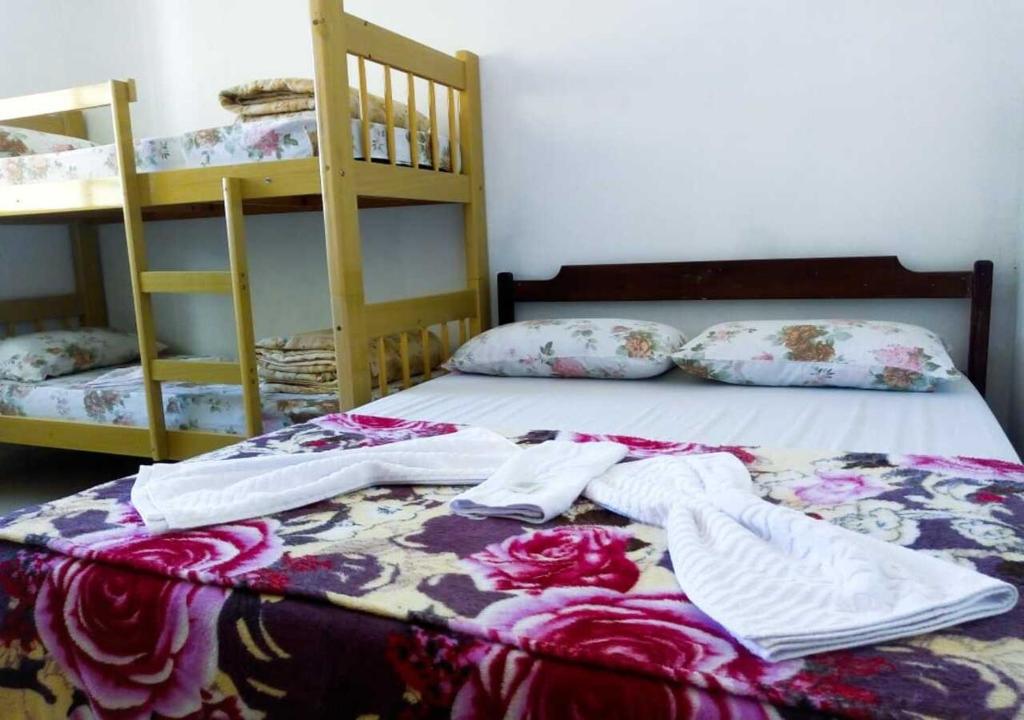 a bed with clothes on it with two bunk beds at Pousada Brasil - Self Check-in in Aparecida
